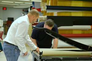 Chris showing Cade Stevens from the Classics Library how to use the board shears to cut his cloth.