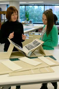 Holly showing Anna how the finished cradle works and why it is such a great tool to have on hand, especially for books being exhibited.